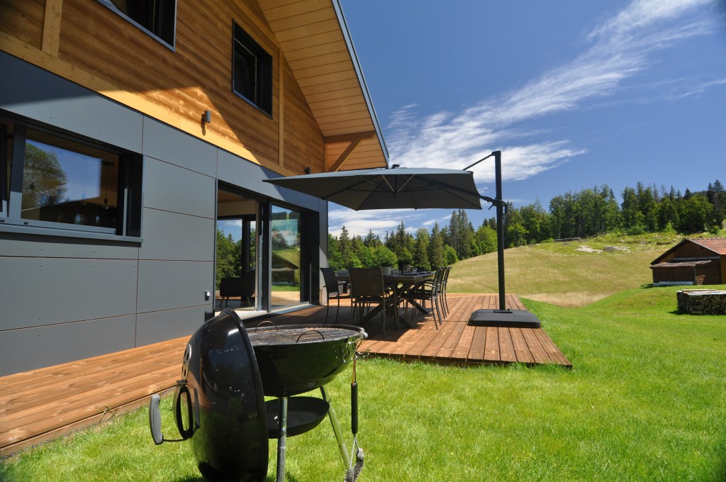 Terrasse chalet prémanon avec parasol et barbecul pour des vacances réussies
